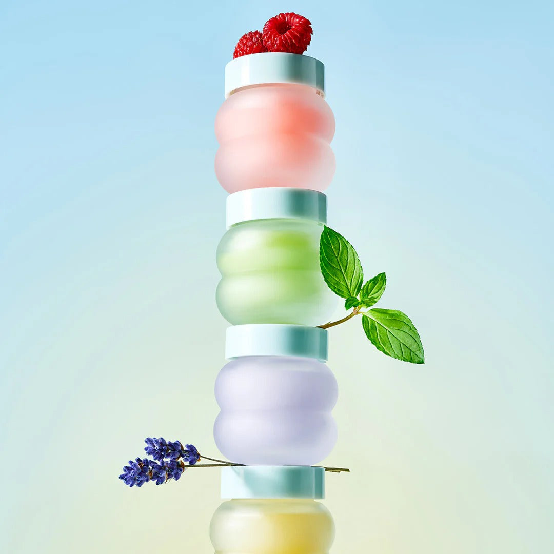 Stack of colorful skincare products with natural elements on a gradient background