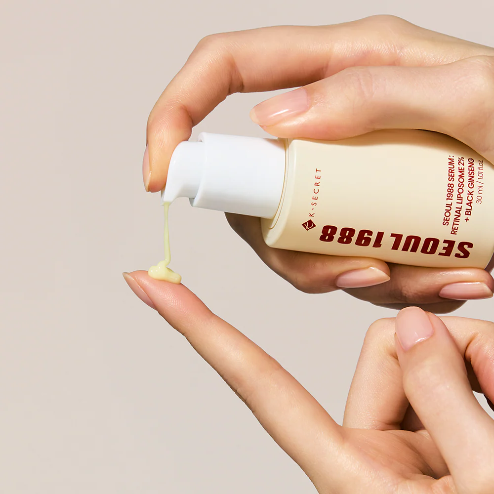 Hand holding a bottle of 'Seoul 1988' skincare serum with cream being squeezed out.