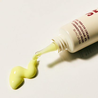 Eye cream bottle with green cream being squeezed out on a light background