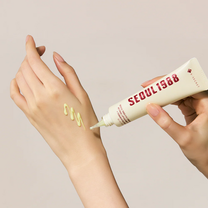 Hand applying cream from a 'Seoul 1988' tube to a wrist with a beige background