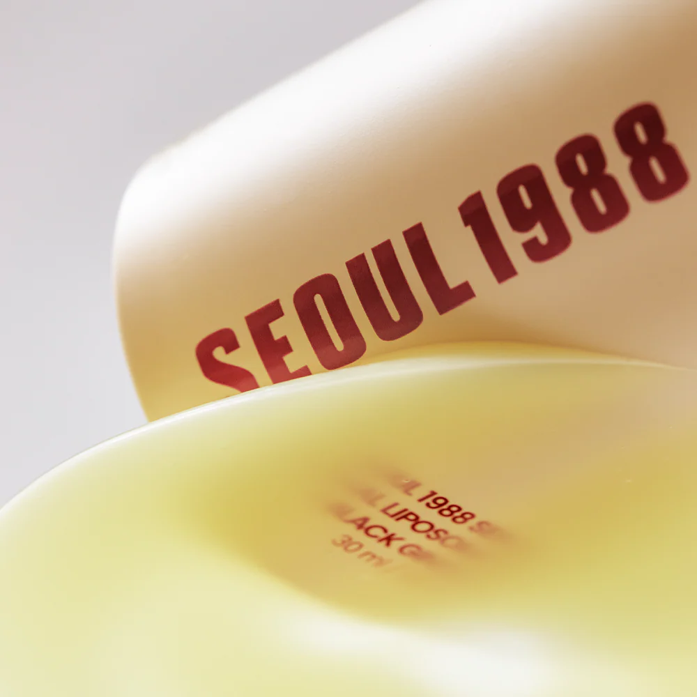 Close-up of a yellow container with 'SEOUL1988' branding on a light gray background