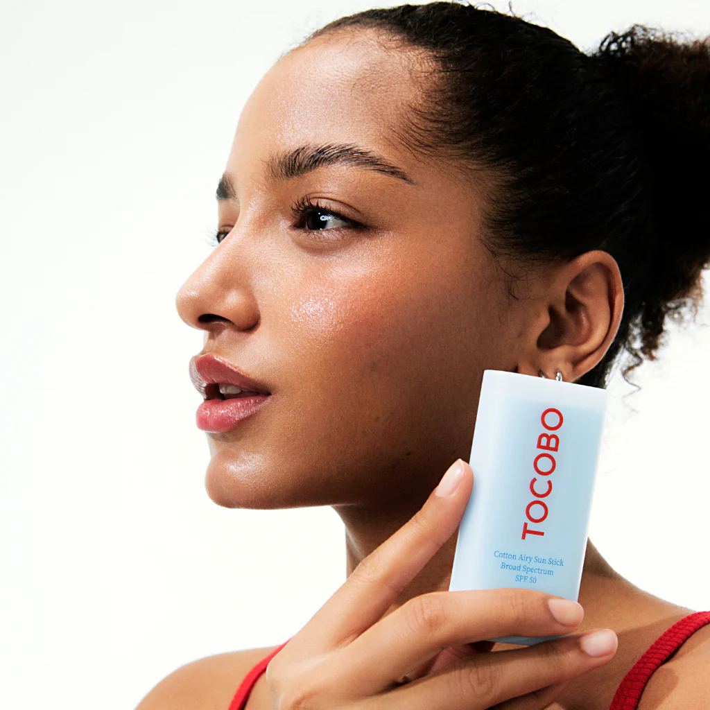 Woman holding a Tocobo skincare product against a white background