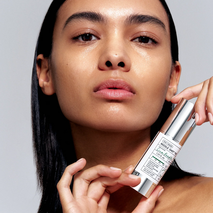 Woman holding a skincare product against a neutral background