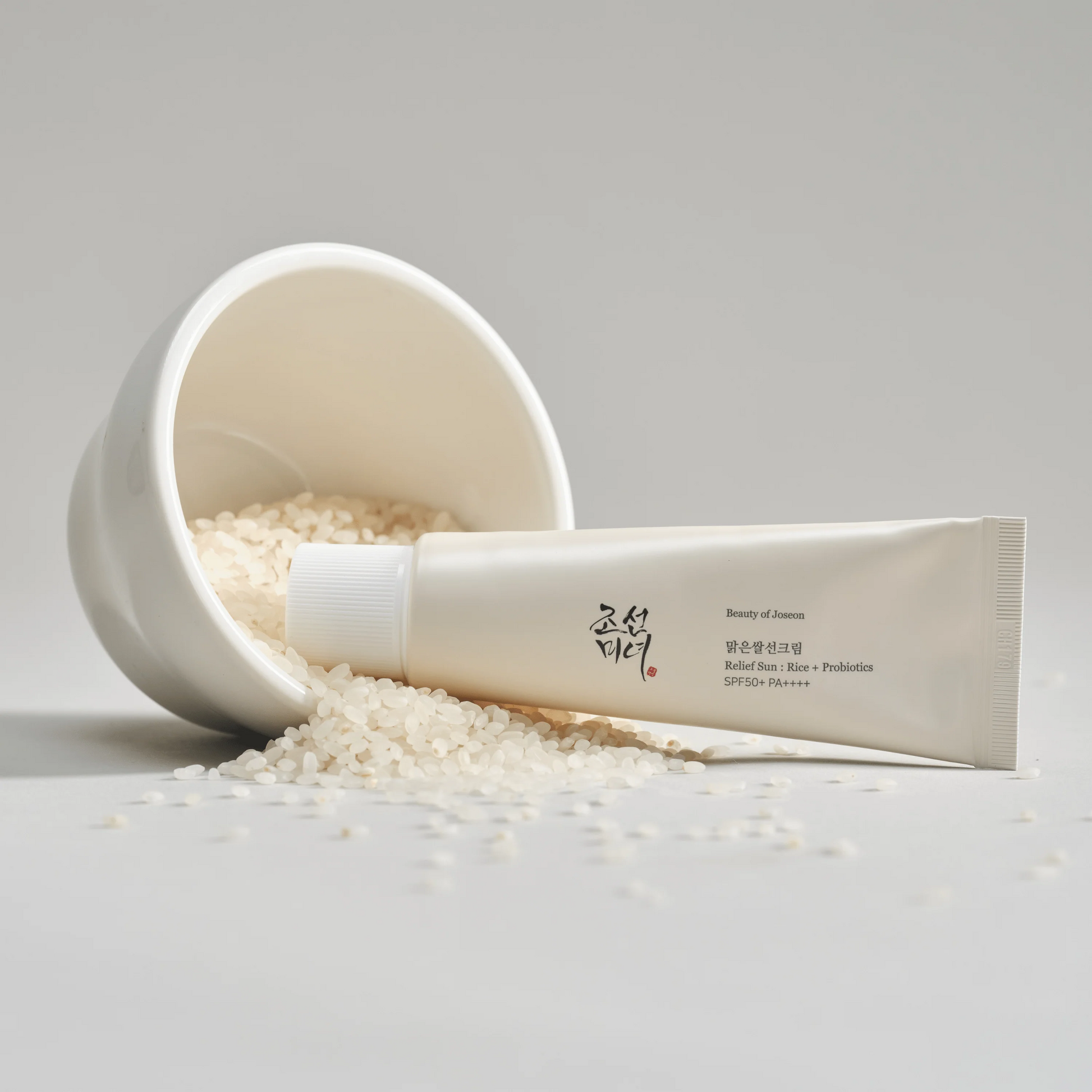 Skincare product with a scoop of rice on a light gray background