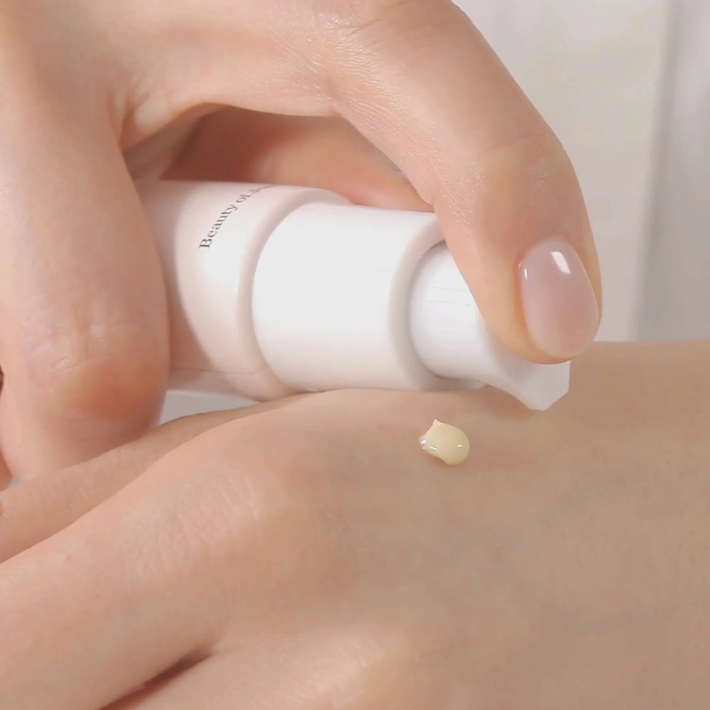 Hand applying a small amount of cream to the skin with a visible brand name.