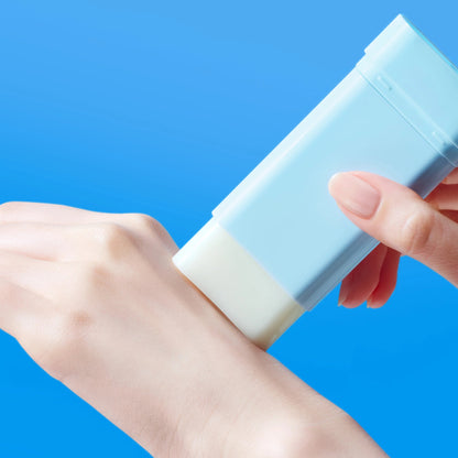 Hand applying a blue and white lotion bar on a blue background