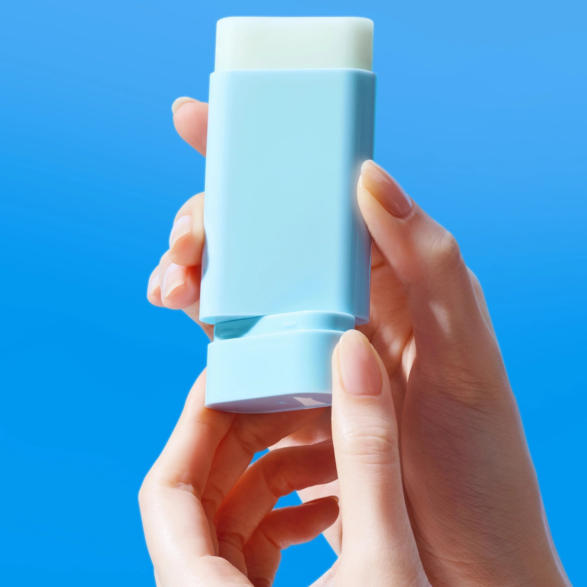 Hand holding a blue stick against a blue background