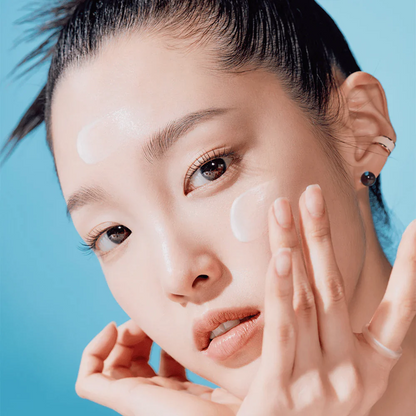 Woman applying cream to her face against a blue background